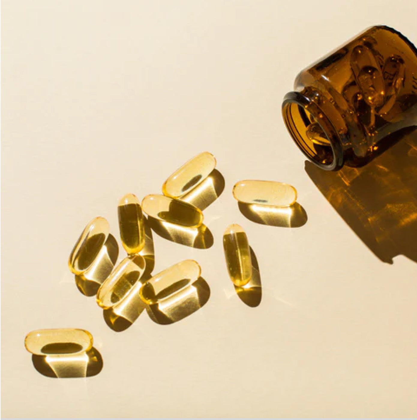 Soft gel capsules pouring out of a glass jar