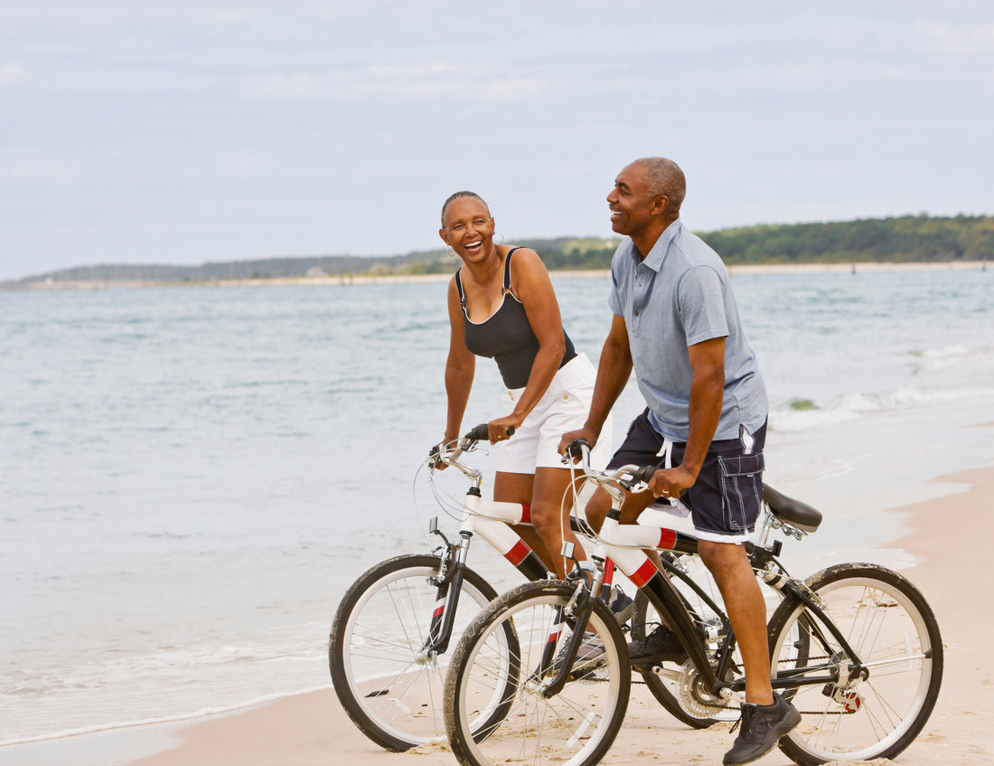 Senior African American couple riding bicycles on a beach.
