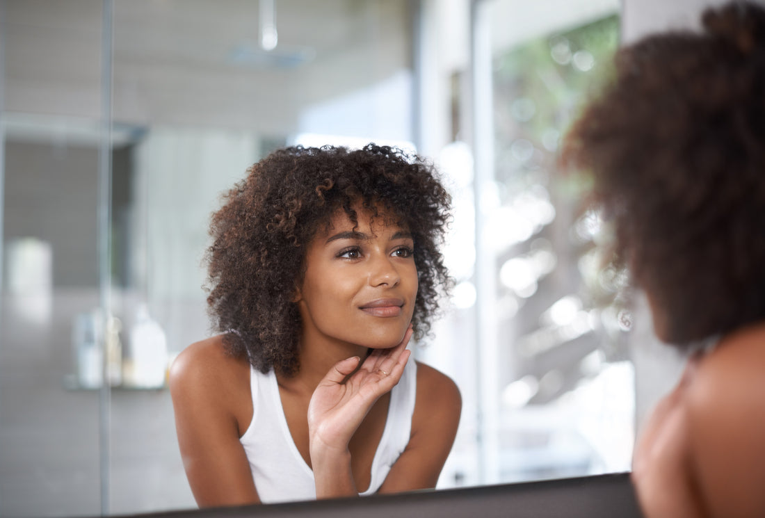 Shot of an attractive young woman looking at herself in the bathroom mirror